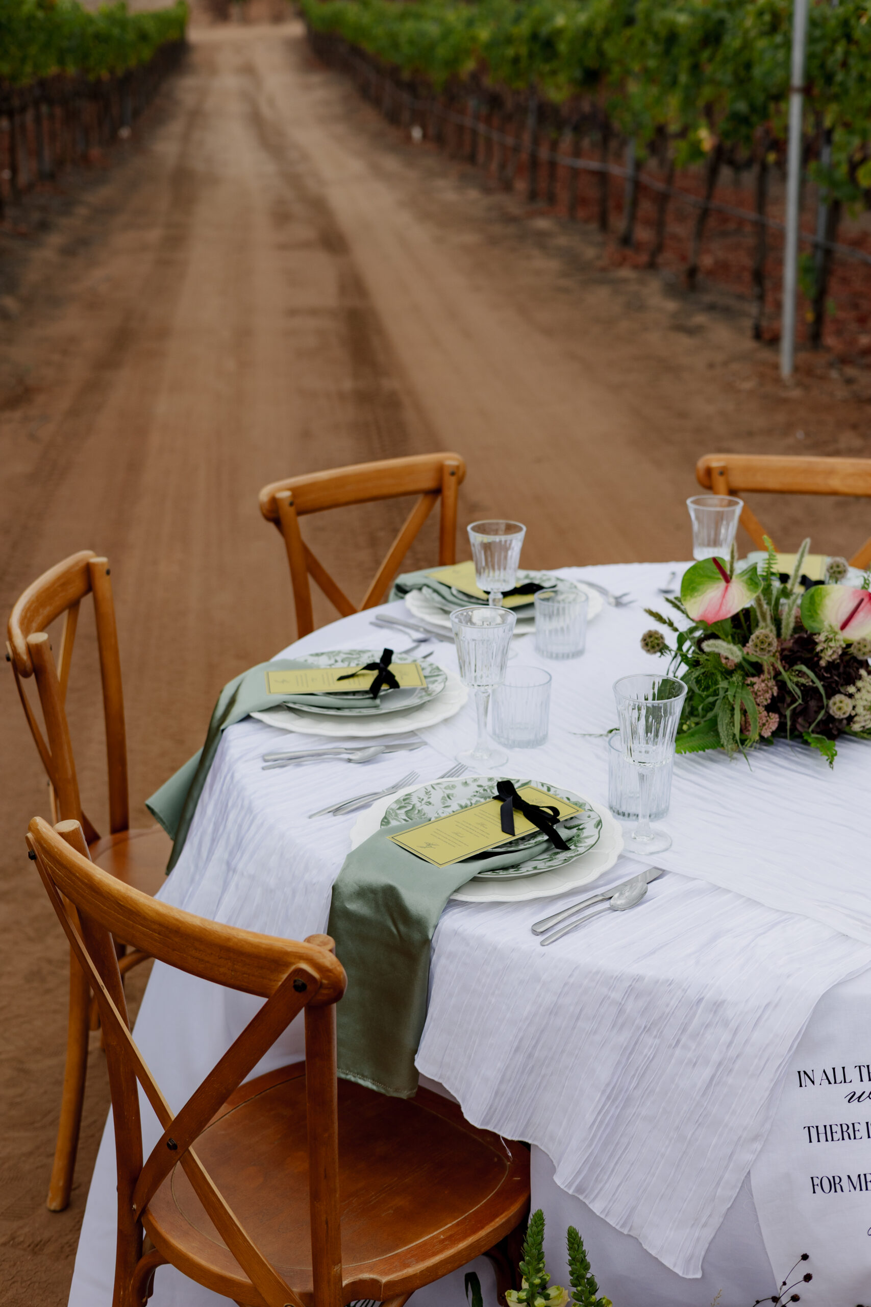 Vineyard reception tablescape with an anthurium and smoke bush centerpiece