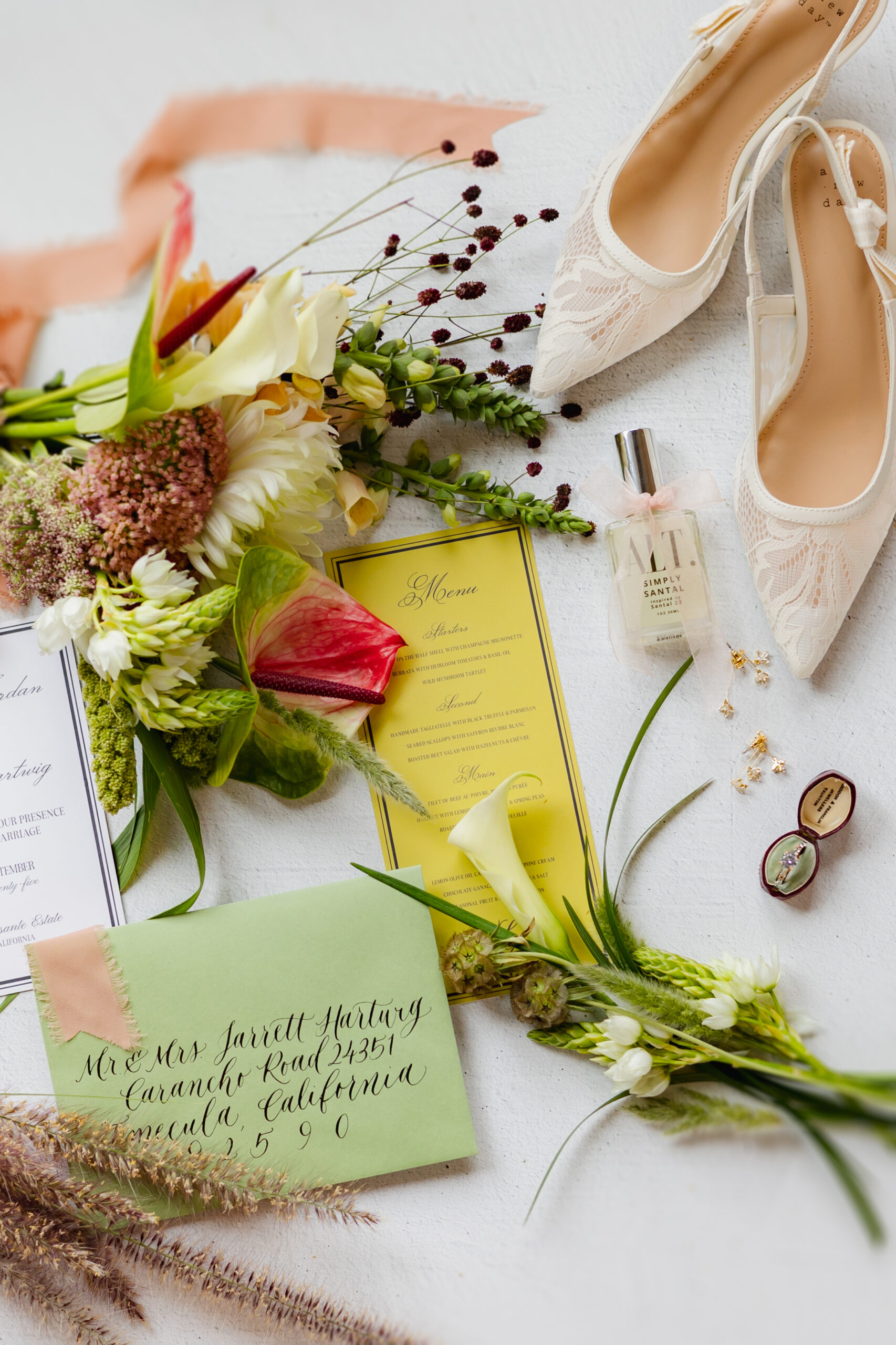 Ivory lace shoes, perfume, and a ring box styled beside a seasonal wedding flowers October bouquet